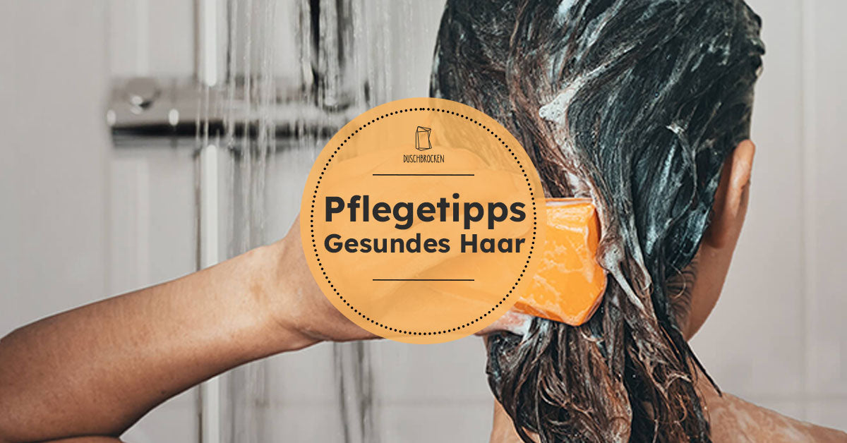 Eine Person wäscht sich die Haare mit Duschbrocken Frida und hält ihn in der linken Hand